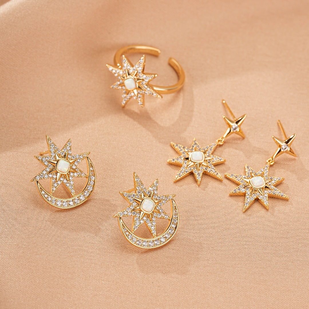 Ensemble de bijoux dorés "Lune Étoilée" comprenant des boucles d'oreilles pendantes, des clous d'oreilles et une bague, ornés de cristaux scintillants et d'une pierre opale centrale.