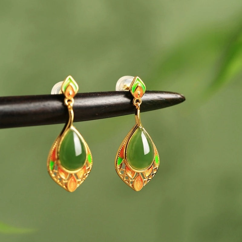 Boucles d'oreilles pendantes ornées de jade vert en forme de goutte, montées sur une monture ajourée plaquée or, décorée d'émaux verts et orangés.