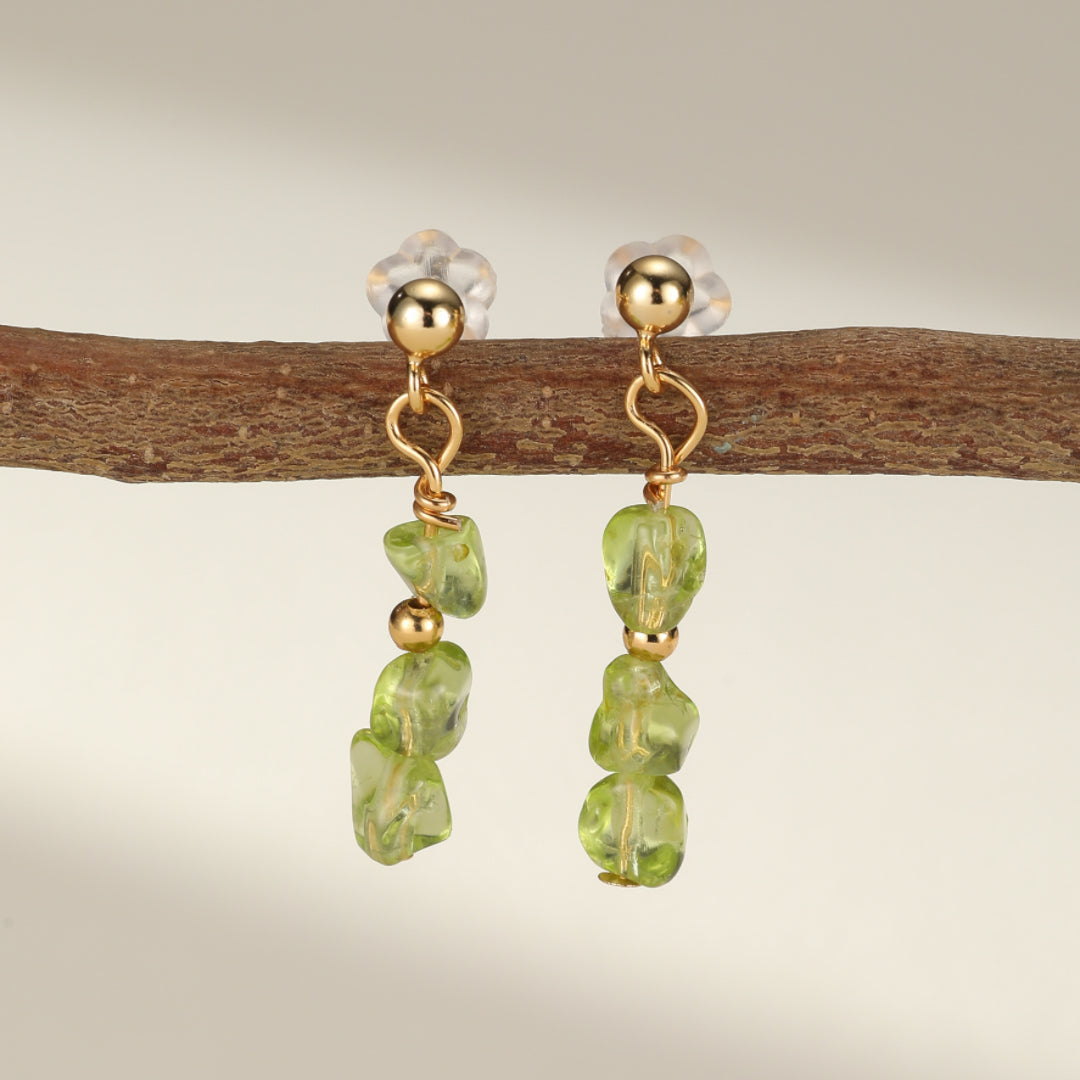 Paire de boucles d'oreilles pendantes en argent plaqué or ornées de trois perles de péridot brutes et d'une perle dorée sur chaque boucle, suspendues à une branche.