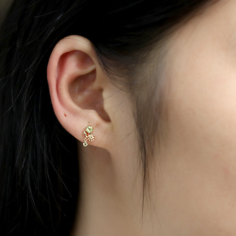 Boucles d'oreilles en argent plaqué or ornées de perles de péridot et de citrine, en forme de fleur ensoleillée, portées à l'oreille.