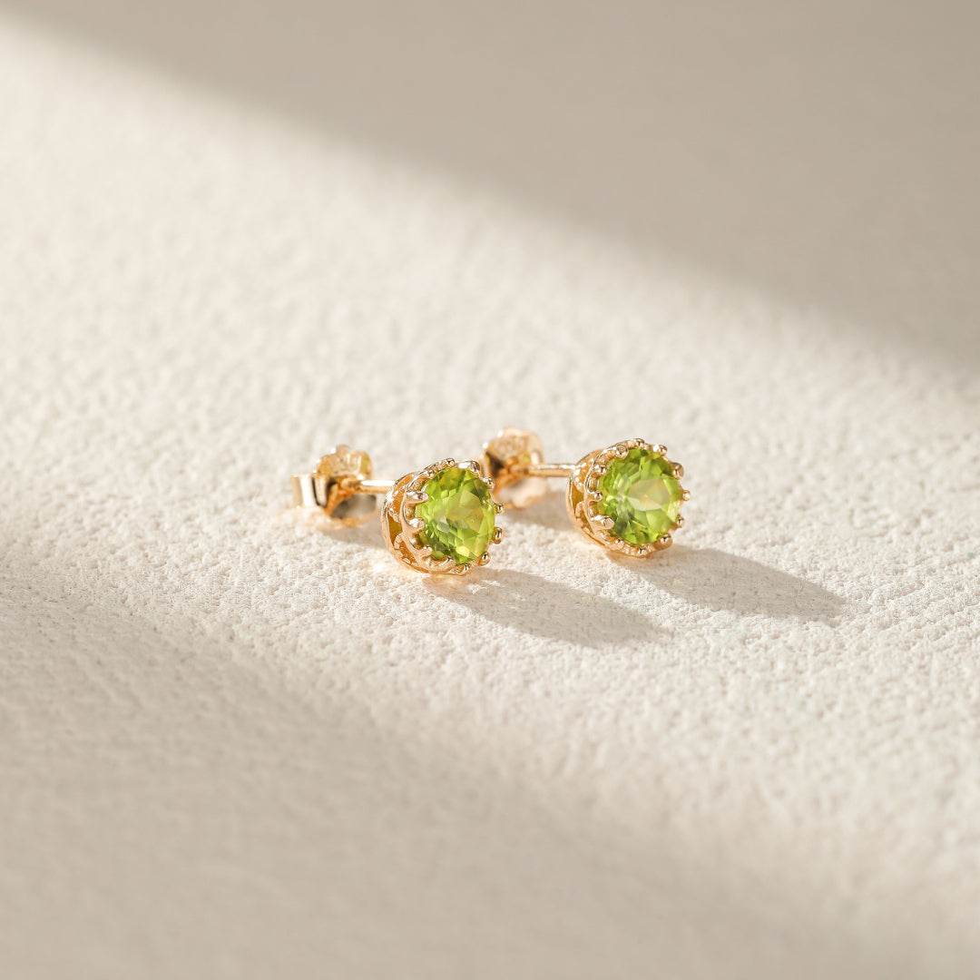 Paire de clous d'oreilles en argent plaqué or avec pierres péridot rondes et monture ajourée inspirée du soleil.