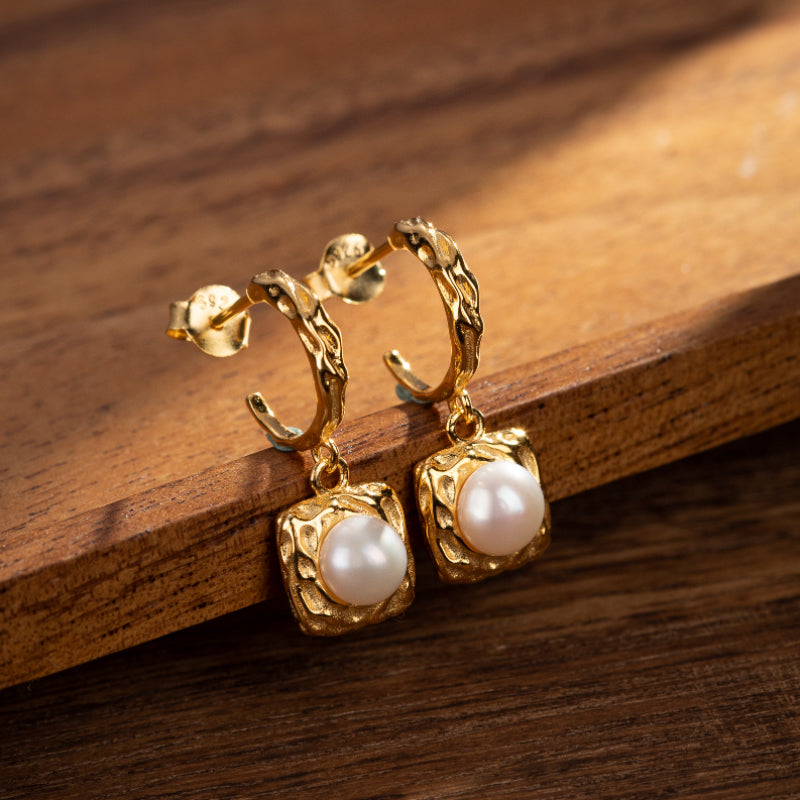 Boucles d'oreilles plaqué or ornées de perles blanches rondes, montées sur un fermoir créole texturé.