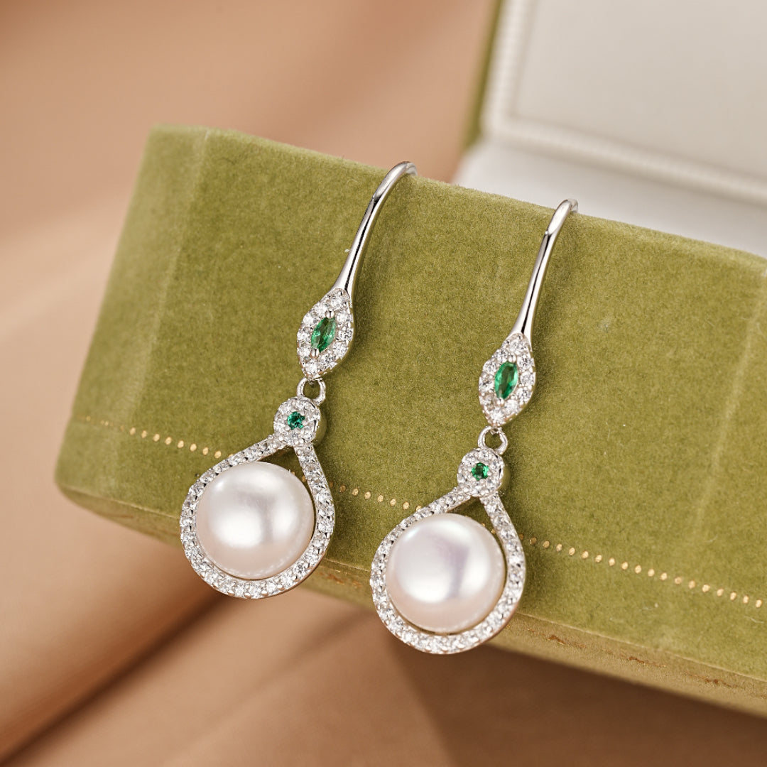 Boucles d’oreilles pendantes en argent 925 ornées d'une perle ronde blanche et de pierres vertes, avec un design élégant et raffiné.