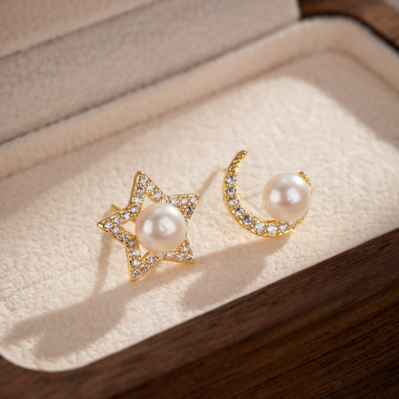 Boucles d'oreilles asymétriques en plaqué or, l'une en forme d'étoile avec une perle et des zircons, l'autre en croissant de lune avec une perle et des zircons.