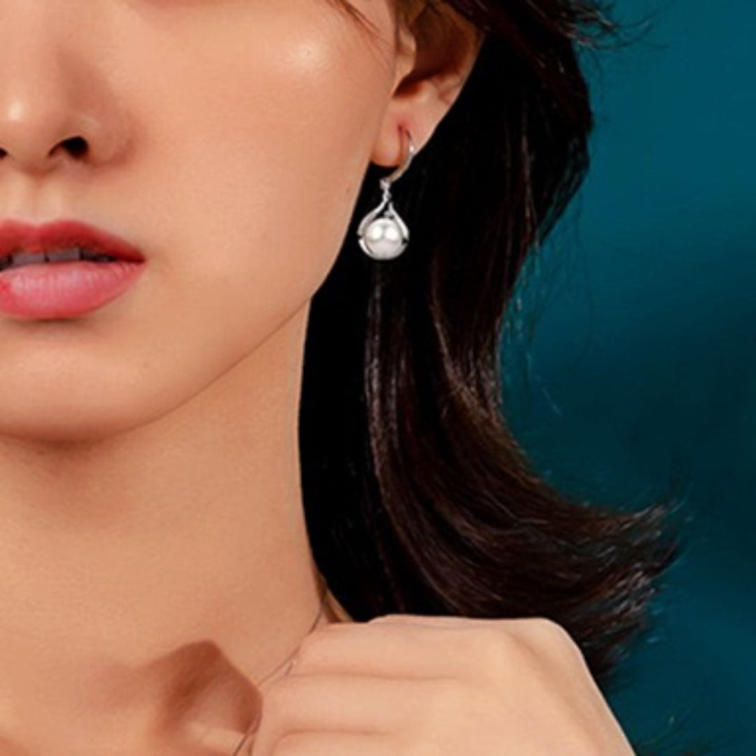 Boucles d'oreilles pendantes en argent ornées d'une perle blanche en forme de goutte, élégant bijou pour femme.