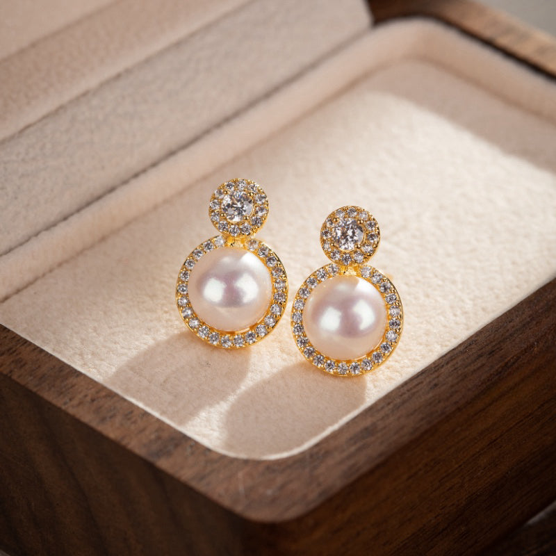 Boucles d'oreilles en perles blanches nacrées et ornées de zirconium, montées sur une monture plaquée or.