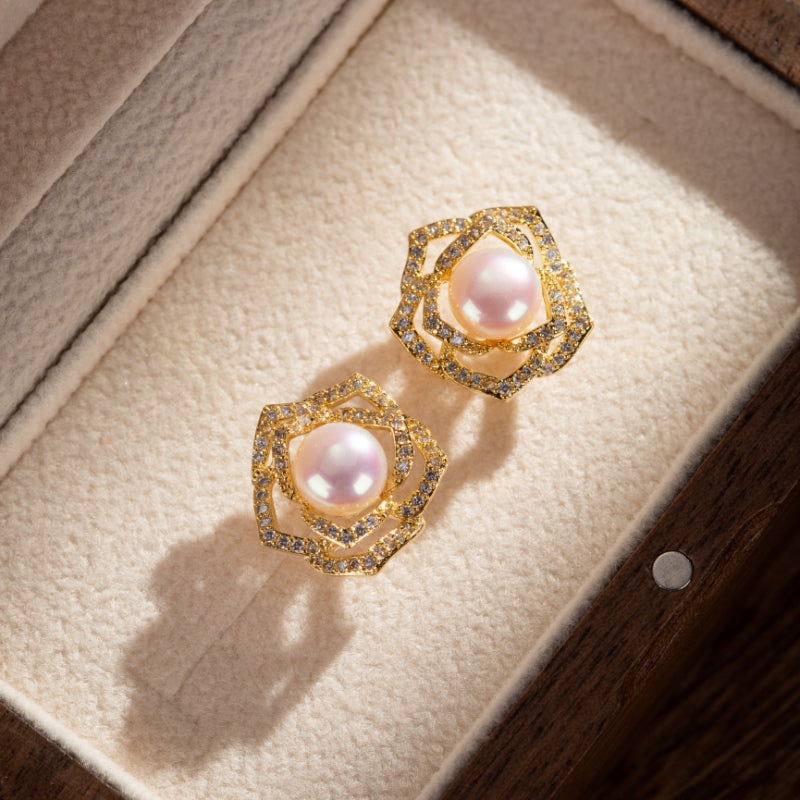 Paire de boucles d'oreilles en forme de rose en argent plaqué or, serties de perles roses et de petits diamants scintillants, présentées dans un écrin