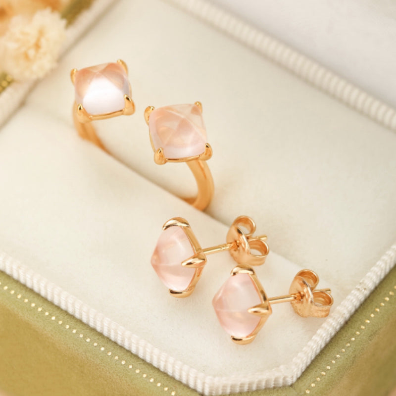Ensemble de bague et boucles d'oreilles en quartz rose taillé en coussin, montées sur de l'argent plaqué or, présentés dans une boîte à bijoux.