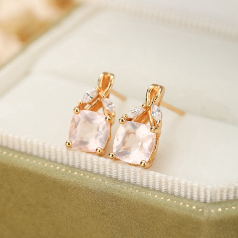 Boucles d'oreilles en argent plaqué or ornées d'un quartz rose carré et de petites pierres blanches en forme de feuilles.