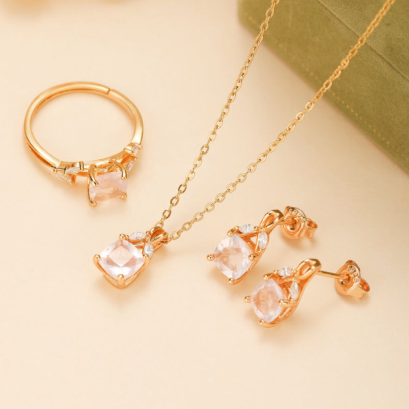 Ensemble de bijoux en argent plaqué or rose, comprenant une bague, un collier et des boucles d'oreilles ornés de quartz rose et de petites pierres scintillantes.