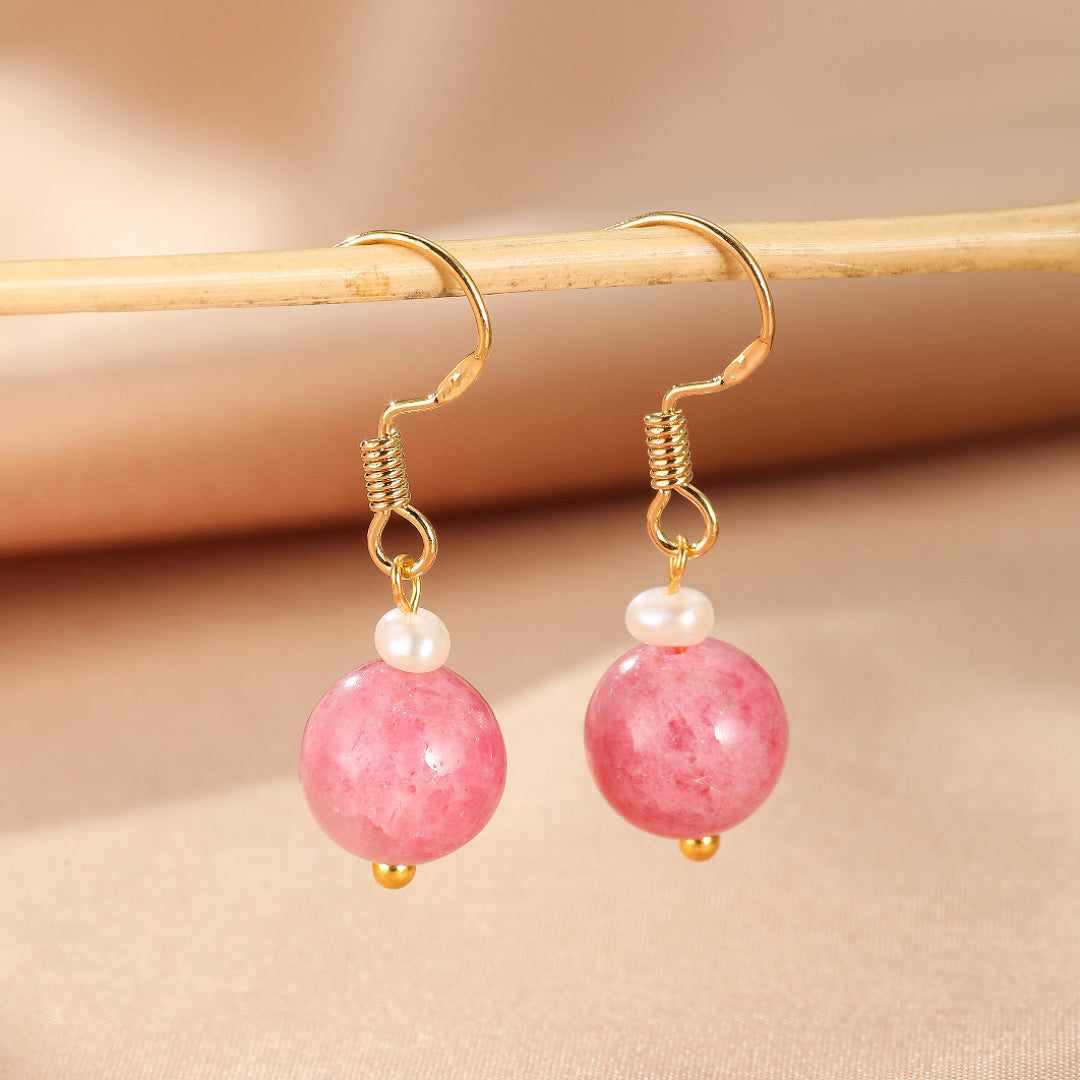 Boucles d’oreilles pendantes en argent plaqué or ornées de perles de rhodonite rose et de petites perles blanches.