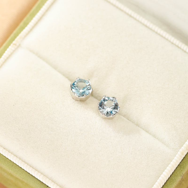 Paire de boucles d'oreilles Topaze bleu clair taillées en brillant, montées sur de l'argent, présentées dans un écrin.
