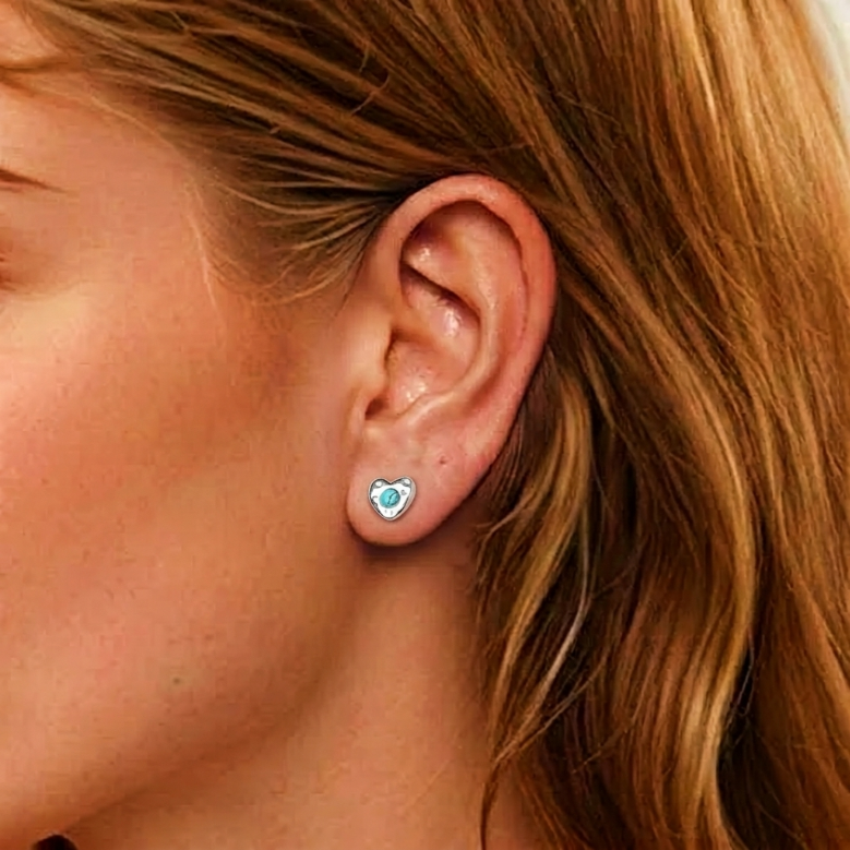 Boucle d'oreille cœur céleste en argent avec une turquoise au centre, portée à l'oreille.