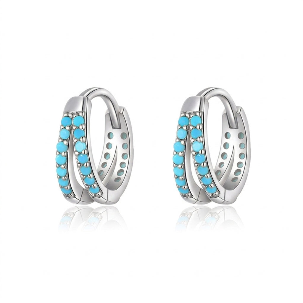 Boucles d'oreilles créoles en argent ornées de doubles rangées de petites pierres turquoise bleues, sur fond blanc
