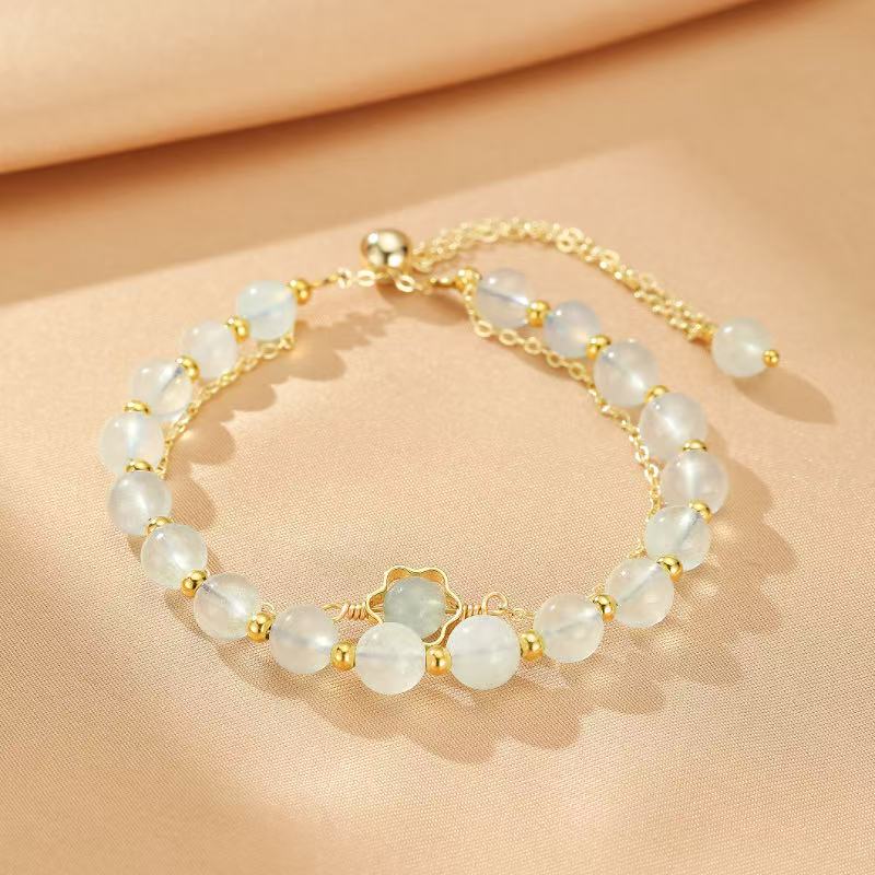 Bracelet "Brillance Océane" en aigue-marine avec des perles bleu pâle et des accents dorés formant une fleur au centre.