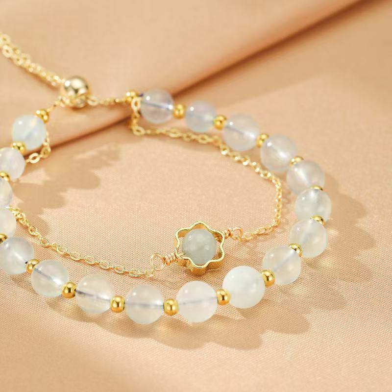 Bracelet double chaîne plaqué or avec perles d'aigue-marine et une petite fleur centrale en pierre d'aigue-marine.