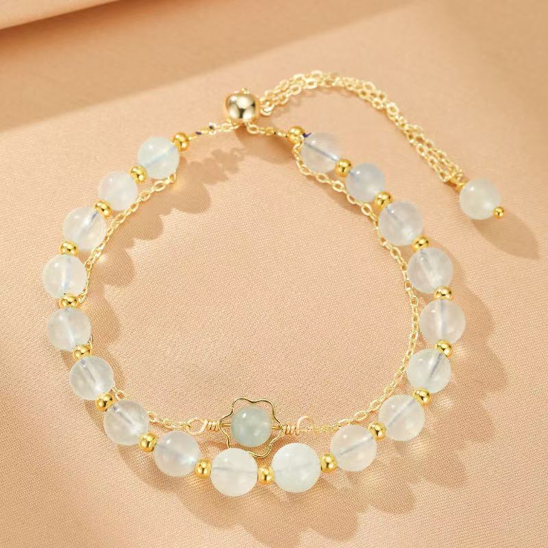 Bracelet en Aigue-Marine "Brillance Océane" avec perles bleues claires et détails dorés, orné d'une petite fleur en aigue-marine.