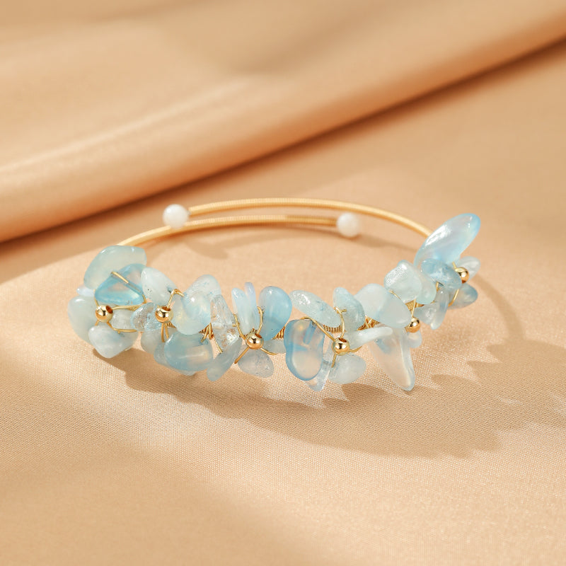 Bracelet jonc rigide doré orné de pierres d'aigue-marine bleues translucides et de petites perles blanches, avec des accents de perles dorées