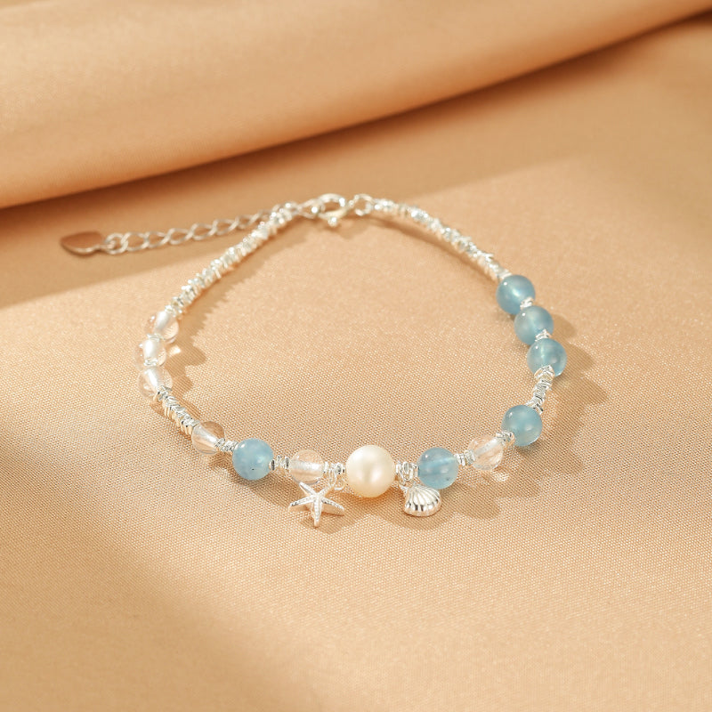 Bracelet "Harmonie Marine" en argent avec des perles d'aigue-marine, une perle nacrée centrale, une étoile de mer et un coquillage.
