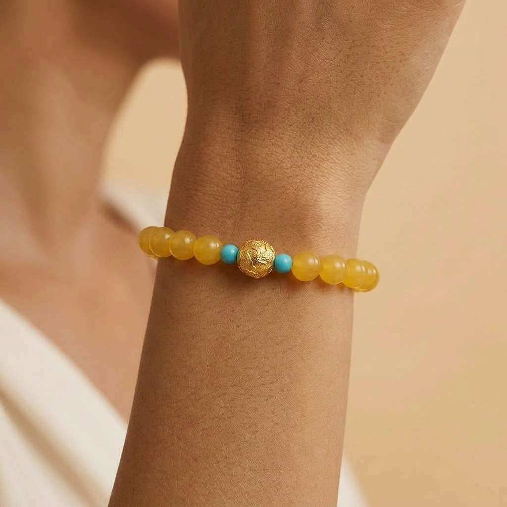 Bracelet Ambre Sève Éternelle composé de perles d'ambre jaune naturel, agrémenté d'une perle centrale dorée texturée et de perles turquoise, porté au poignet.