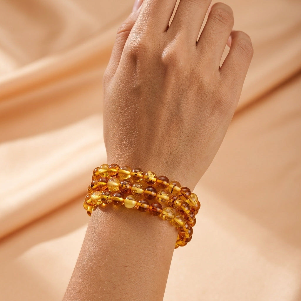 Bracelet en perles d'ambre naturel modèle Souffle Ancien porté au poignet sur un fond en tissu satiné beige