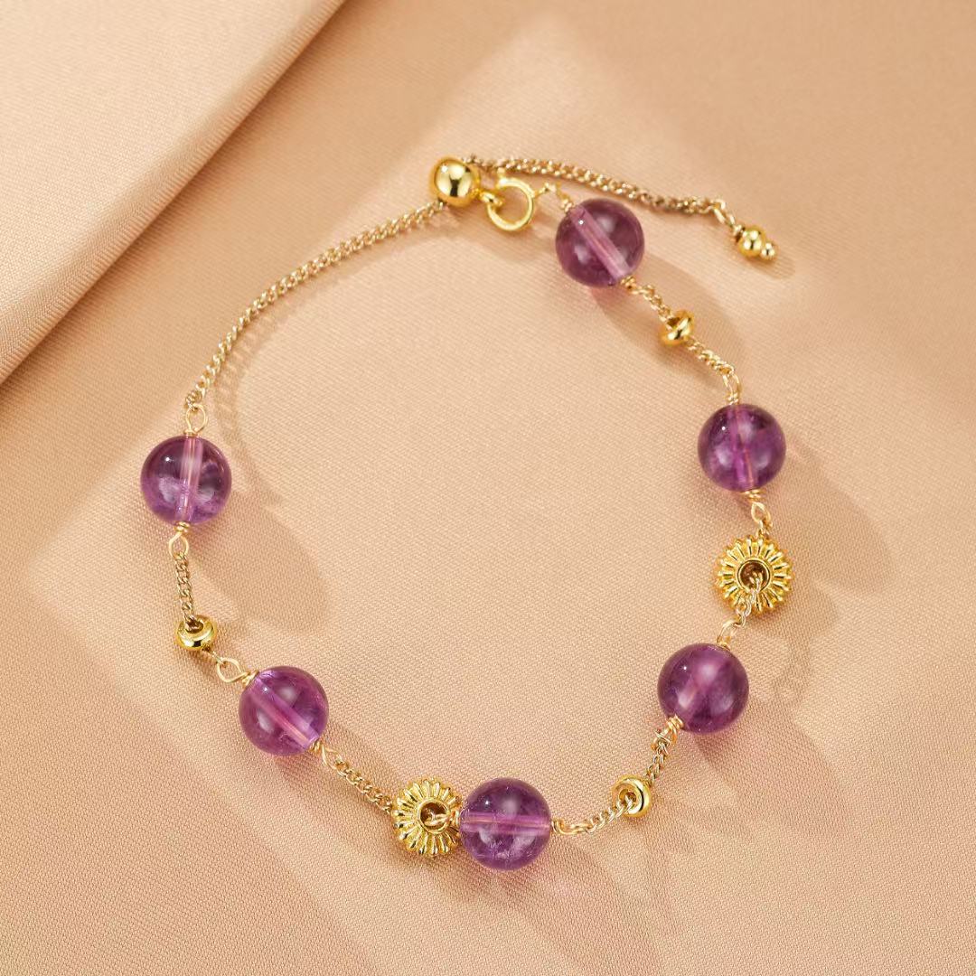 Bracelet ajustable en argent plaqué or avec des perles d'améthyste et des breloques en forme de soleil.