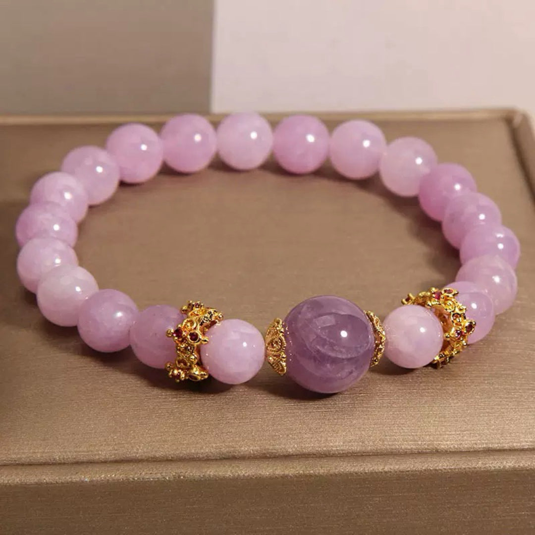 Bracelet fait de perles d'améthyste violettes et de perles roses pâles, avec des ornements dorés entre les perles.