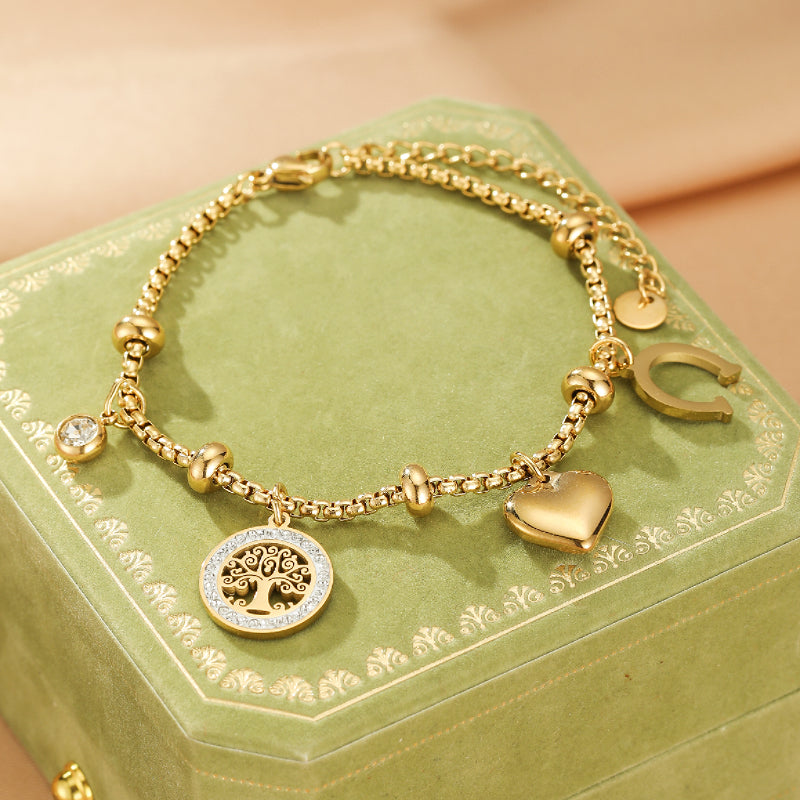 Bracelet Arbre de Vie – Lumière de Vie en acier inoxydable doré, orné d'un pendentif arbre de vie serti de cristaux, d'un cœur, d'un fer à cheval et d'une pierre d'imitation.