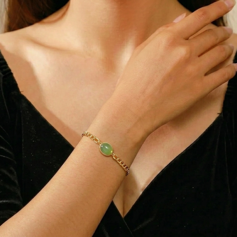 Bracelet Aventurine – Ivresse du Ciel, avec une chaîne dorée et une pierre ovale verte au centre, porté au poignet d'une femme.