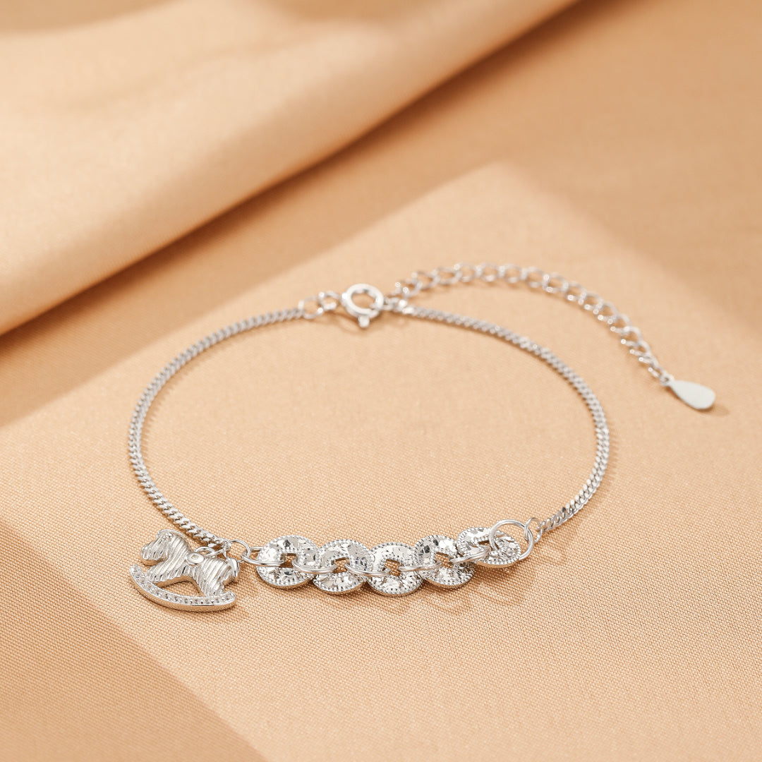 Bracelet en argent avec un pendentif cheval à bascule orné de zircons et cinq charms ronds ajourés, fermoir mousqueton