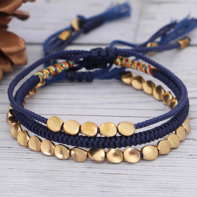 Trois bracelets en cordon bleu marine ornés de perles dorées plates et d'une touche de fil coloré, de la marque Pulse Paix.