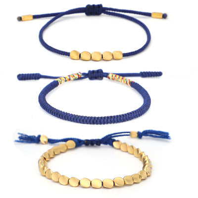 Trois bracelets en cordon bleu avec des perles dorées. Un bracelet est orné de cinq perles carrées dorées, un autre présente une tresse colorée et le troisième est entièrement composé de perles dorées plates.