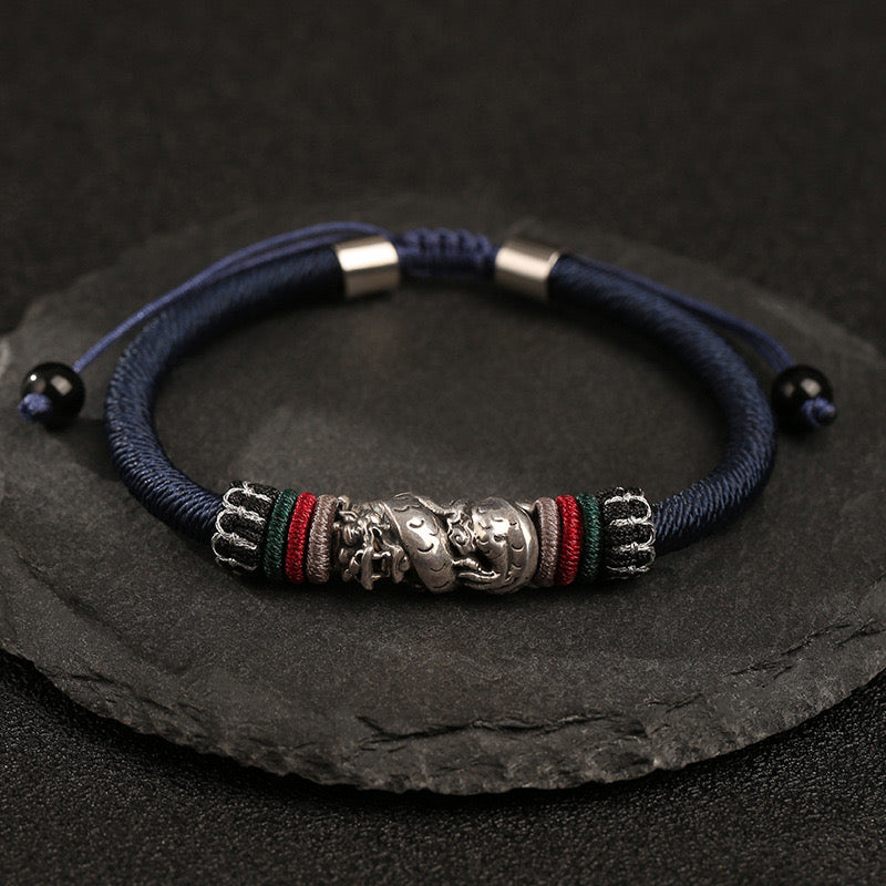 Bracelet cordon bleu avec un pendentif dragon en argent, accents de fils colorés et perles noires.