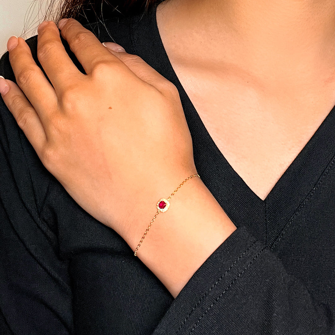 Bracelet fin en argent avec une cornaline rouge centrale entourée de zirconiums, porté au poignet d'une femme.