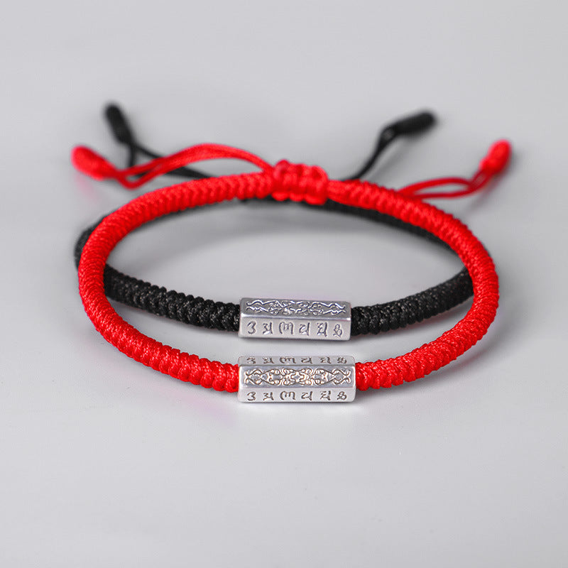 Deux bracelets "mantra" en fil rouge et noir, avec des pendentifs rectangulaires en argent gravés de caractères bouddhistes.