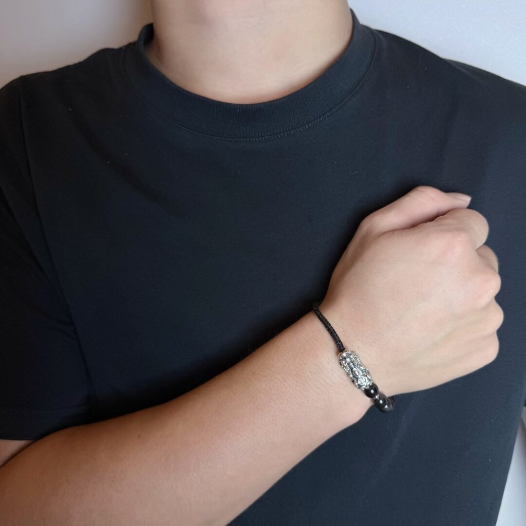 Bracelet Pi Xiu en fil rouge avec perles noires, porté au poignet d'un homme
