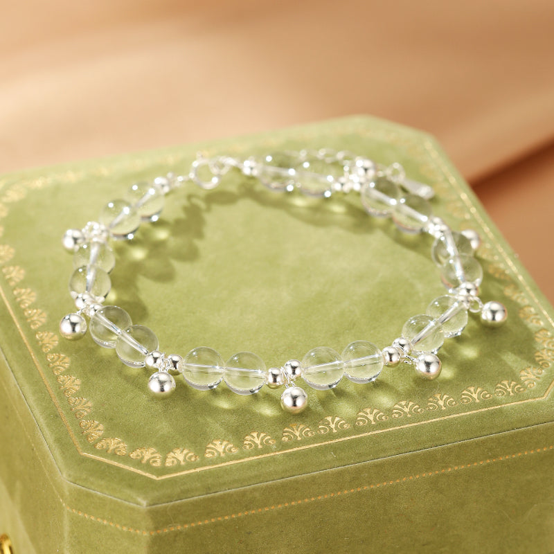 Bracelet en cristal de roche transparent avec de petites perles argentées et des breloques boule argentées, monté sur une chaîne argentée délicate.