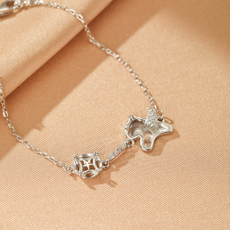 Bracelet en argent avec un pendentif de licorne ailée orné de cristaux et un pendentif carré en cristal de roche.