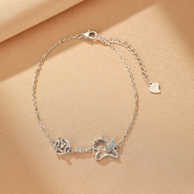 Bracelet en argent avec pendentif cheval ailé en cristal et motif rond ajouré, orné de petites pierres scintillantes.