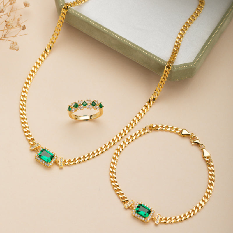 Ensemble de bijoux plaqué or avec un bracelet, un collier et une bague ornés de pierres d'émeraude rectangulaires et de zirconiums blancs.