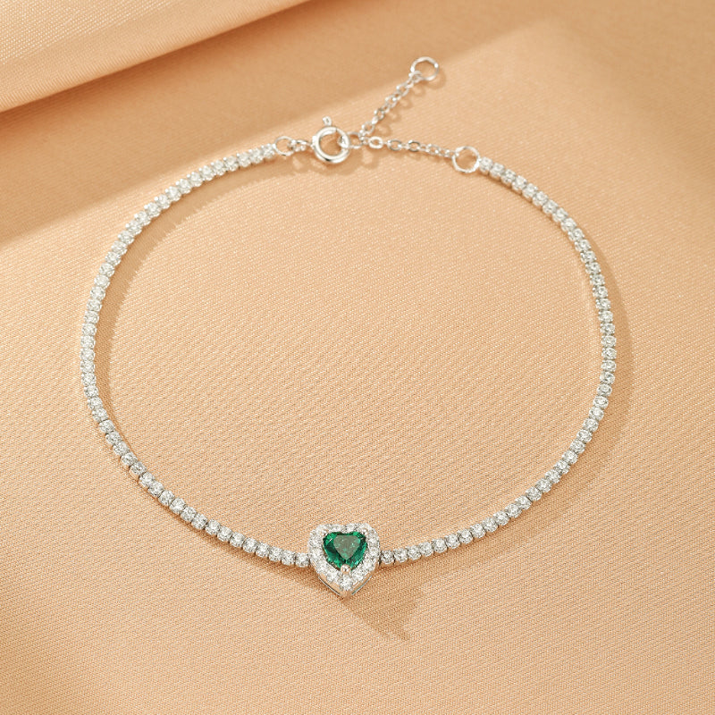 Bracelet fin en argent 925 avec une chaîne tennis sertie de zircons blancs et un pendentif en forme de cœur émeraude au centre.