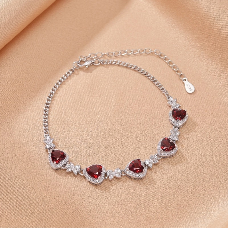 Bracelet en argent 925 orné de multiples cœurs en grenat rouge sertis de cristaux scintillants, avec une chaîne fine et un fermoir réglable.