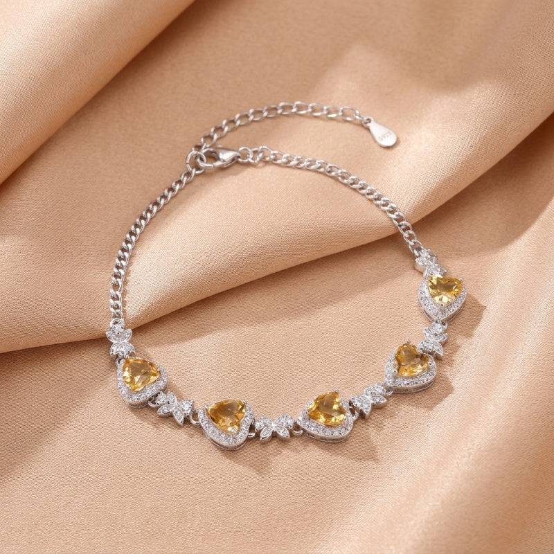 Bracelet en argent 925 serti de citrines en forme de cœur et de zircons cubiques scintillants, disposés en alternance avec des motifs floraux délicats.