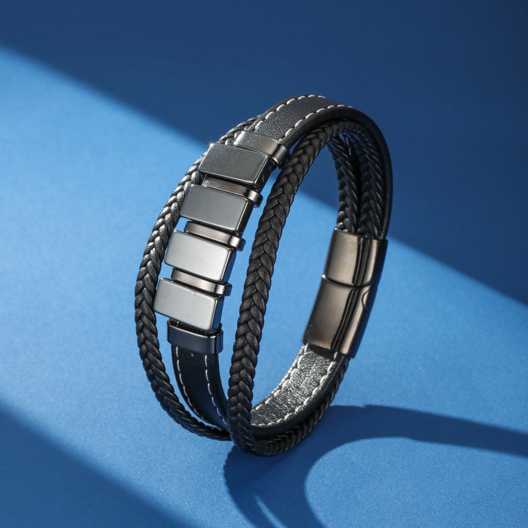 Bracelet homme en cuir tressé noir avec une rangée de carrés en hématite et un fermoir magnétique.