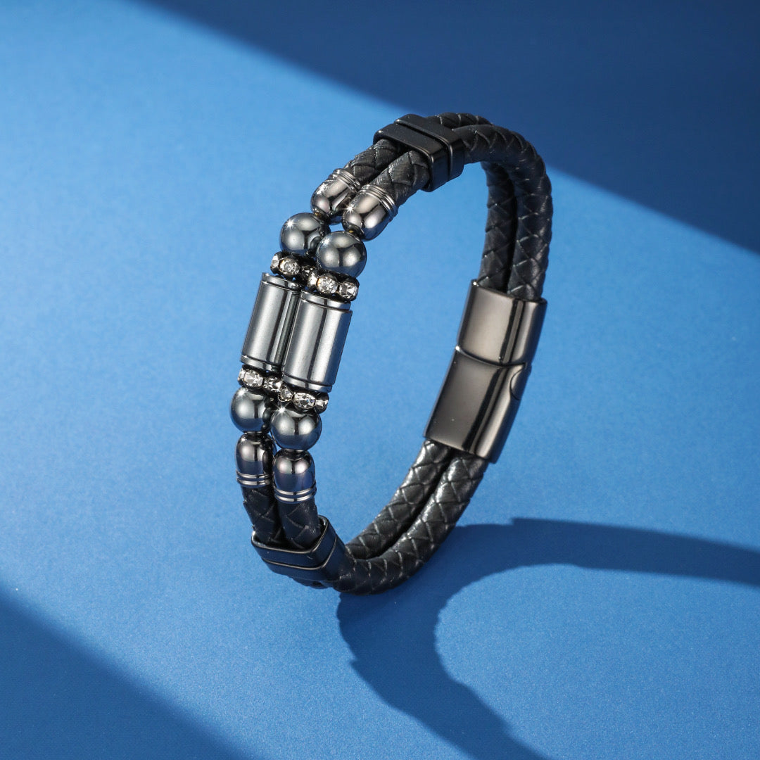 Bracelet homme double rang en cuir tressé noir, orné de perles d'hématite et de cylindres métalliques sertis de strass, avec un fermoir magnétique noir.