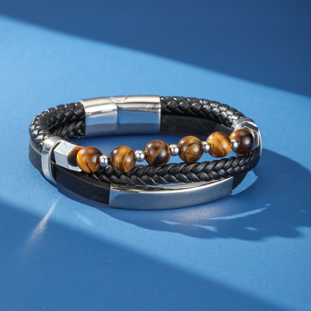 Bracelet homme multicouche en cuir noir tressé et lisse, orné de perles naturelles d'œil de tigre et d'un fermoir magnétique argenté.