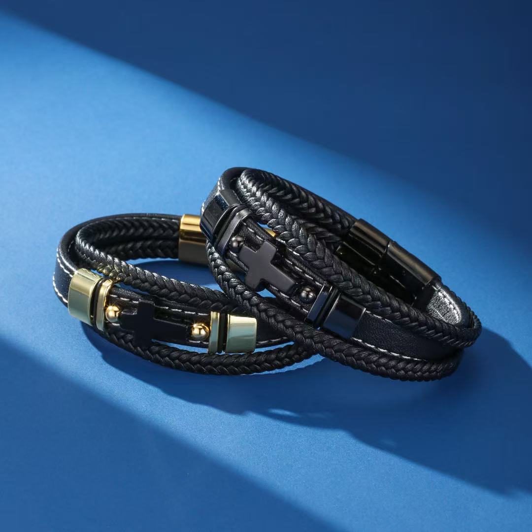 Bracelet homme en cuir noir tressé avec perles d'onyx et fermoir orné d'une croix, sur fond bleu.