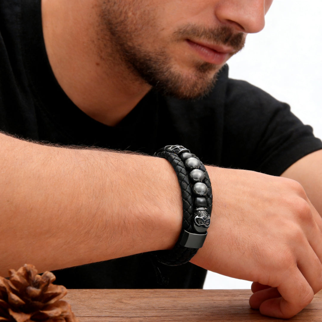 Bracelet homme cuir tressé noir avec perles rondes argentées et breloques tête de mort, fermoir métallique.