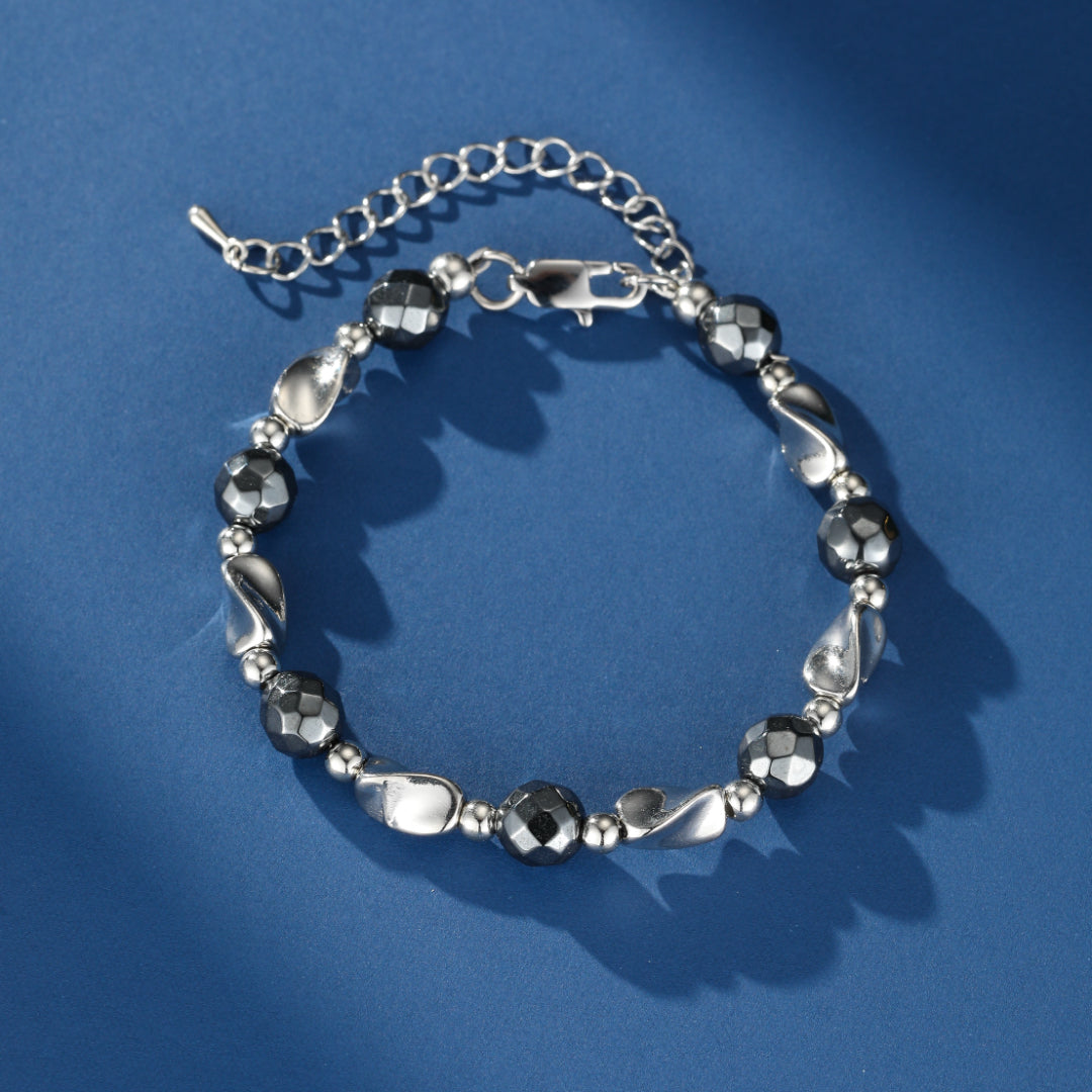 Bracelet pour homme en hématite facettée et perles argentées polies, sur fond bleu.