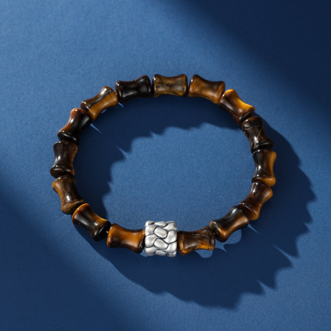 Bracelet homme en œil de tigre avec des perles sculptées en forme de bambou et une perle centrale argentée texturée.